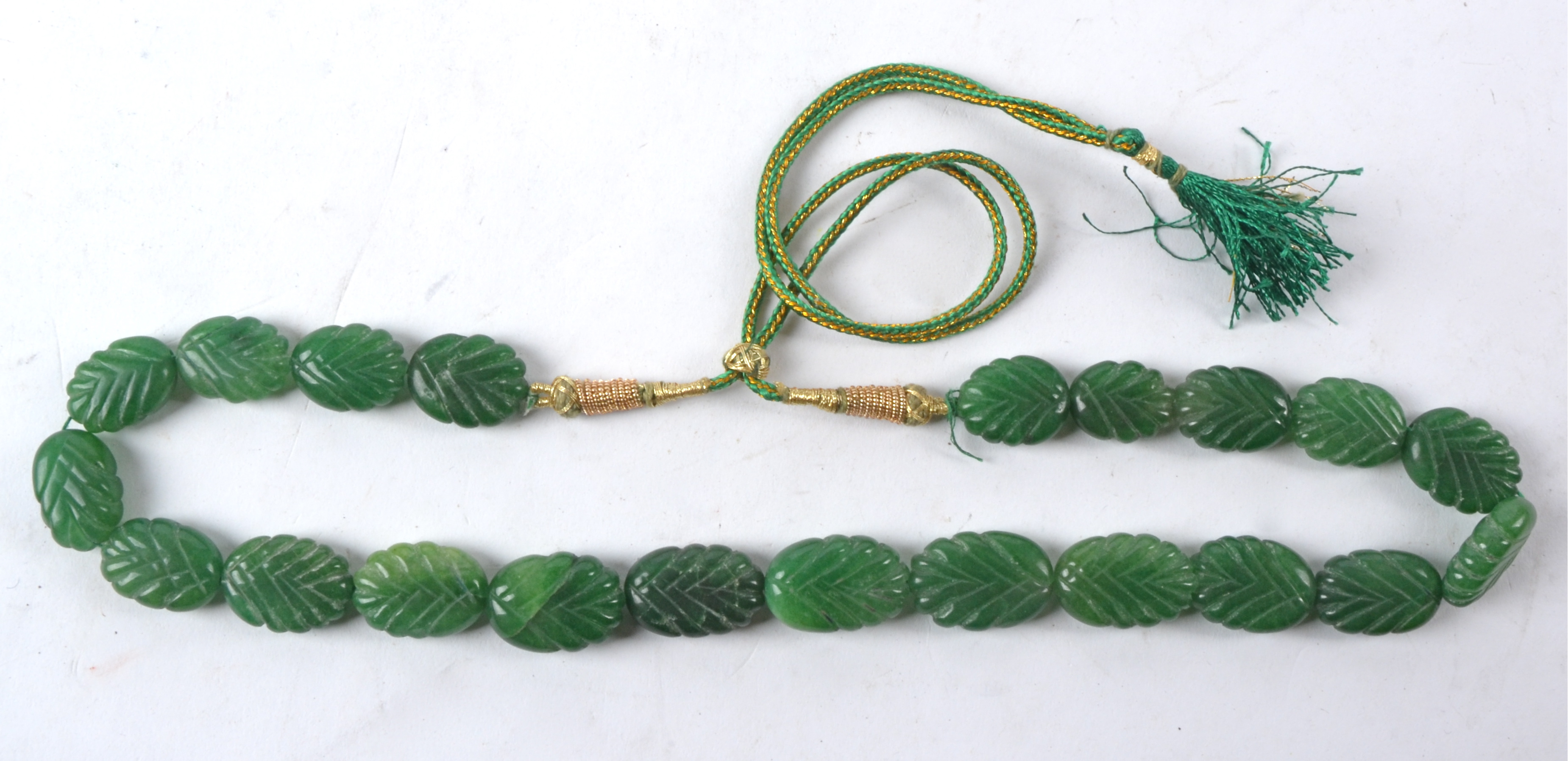 An Asian green hardstone bead necklace each section in the form of a leaf, on a gilt and green - Image 2 of 3