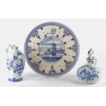 Three pieces of blue and white Delft pottery, two jugs and a plate, each with a cartouche showing