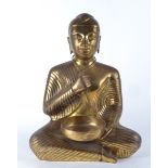 A large brass figure of a cross legged Buddha, seated in the lotus position and holding an empty