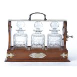 A 20th Century oak Tantalus with silver plated mounts, with three decanters and multifaceted