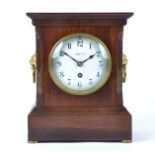 An early 20th century stained oak mantel clock, circular enamel dial with Arabic numerals