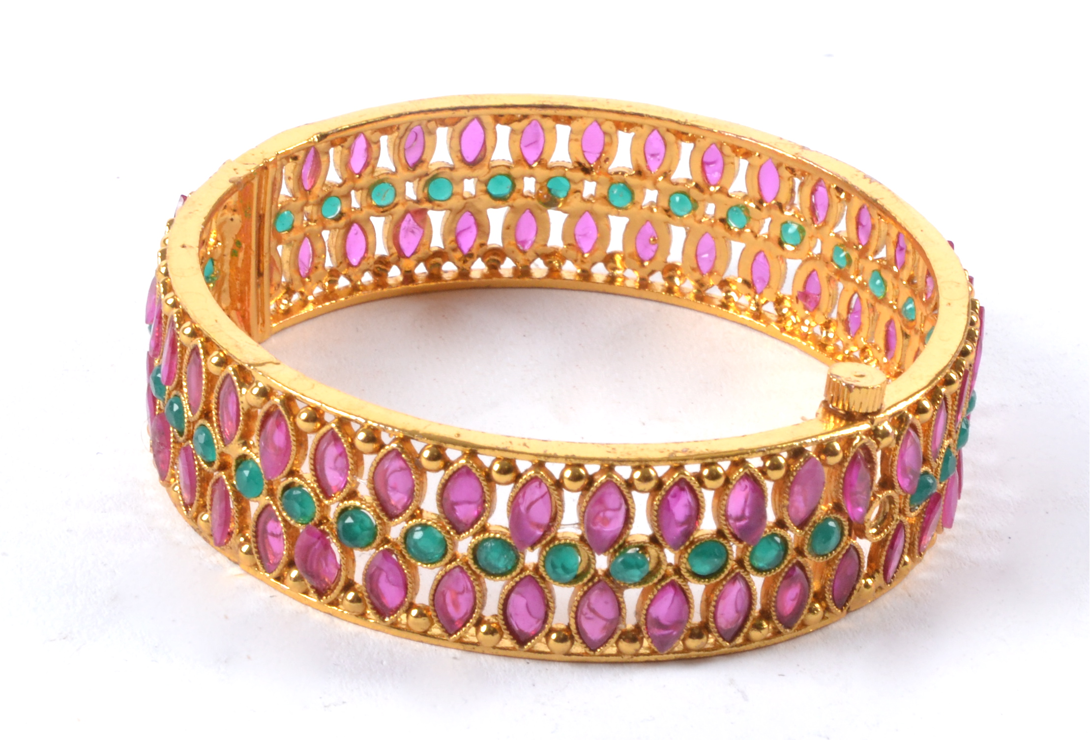 A decorative gilt bangle with semi precious red and green stones in the manner of rubies and