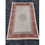 A Peking Oriental rug with central shou symbol, on a cream ground with a key fret border, 187cm x
