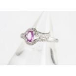 A contemporary pink sapphire and diamond dress ring, with oval mixed cut central pink sapphire