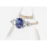 A sapphire and diamond three stone ring, the oval mixed cut claw set sapphire flanked by a pair of