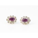 A pair of ruby and diamond oval cluster earrings, the oval mixed cut central claw set rubies