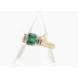 A contemporary 18ct gold three stone emerald and diamond ring, the emerald cut in claw setting