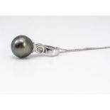 A cultured black pearl and diamond drop pendant, in white metal marked 14k 585 on a fine 9ct white