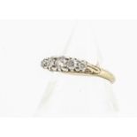 An early 20th Century 18ct diamond five stone dress ring, the old cuts in white tipped scroll