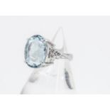 An aquamarine and diamond platinum set dress ring, the oval mixed cut aquamarine in four claw