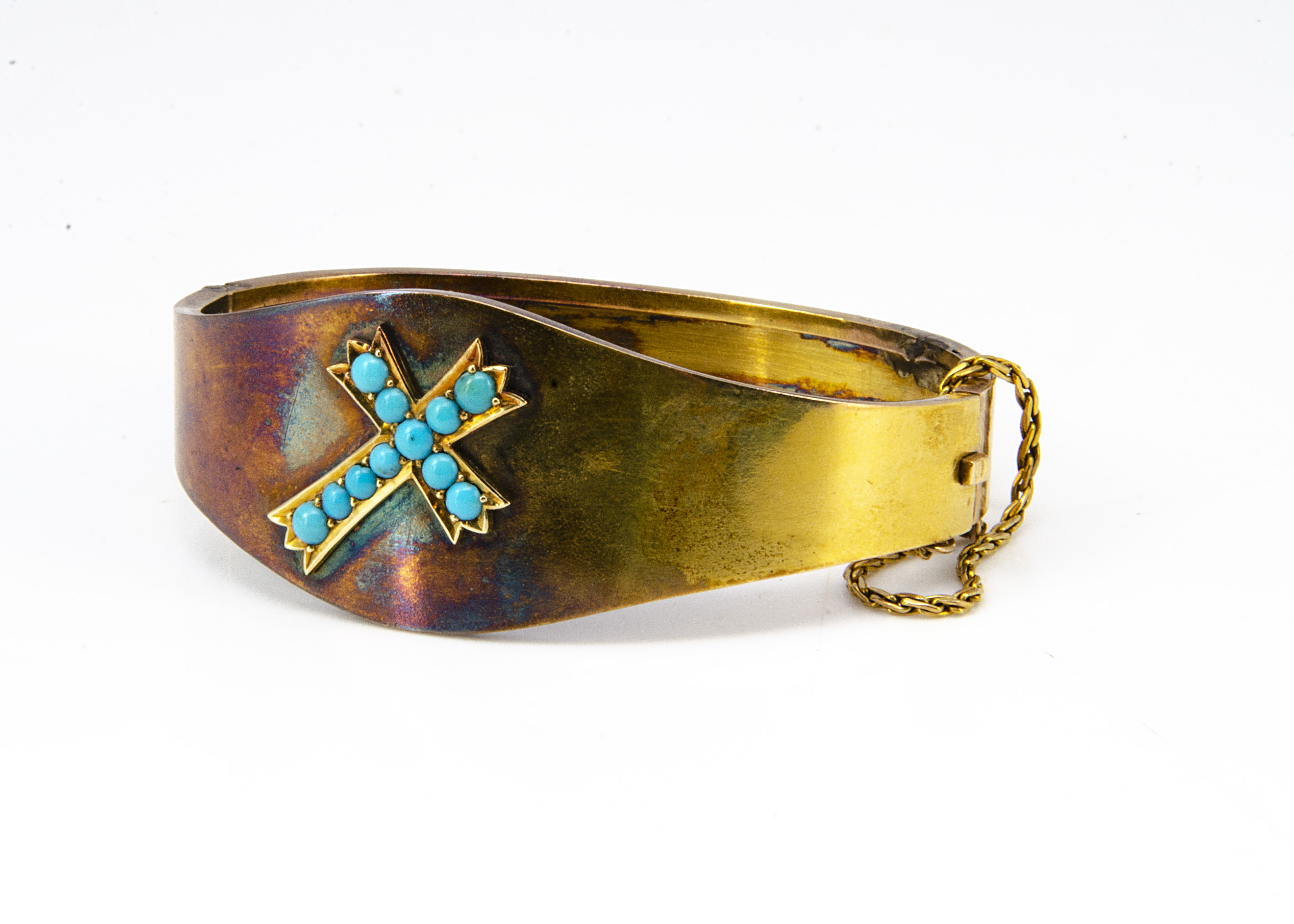 An Edwardian yellow metal and turquoise bangle, the ovoid hinged top with central decoration of