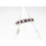 A white metal ruby and diamond half hoop eternity ring, the mixed rectangular cut rubies alternately