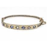 An early 20th Century yellow metal sapphire and diamond bangle, the satin top set with old cut