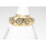 A Victorian 18ct gold three stone diamond ring, the three old cuts in gypsy setting dated Birmingham