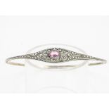 A Belle Epoque costume arm bangle, set with an oval pink paste stone, within a white metal setting