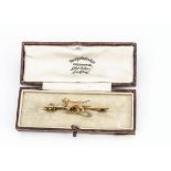An early 20th Century dog bar brooch, the yellow metal bar marked 9ct surmounted with a working dog,