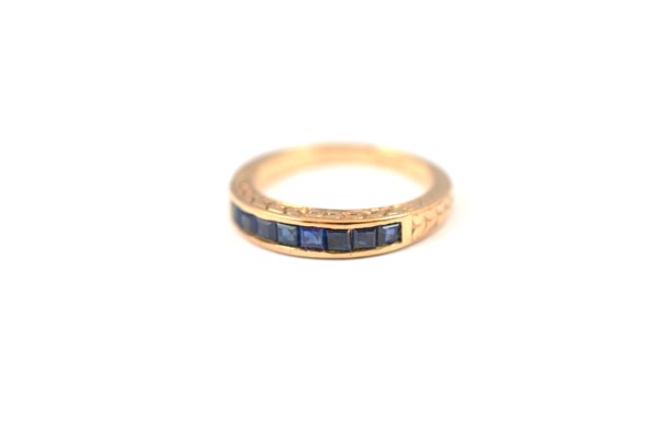 A 9ct half hoop sapphire ring, the square cut channel set sapphires within an engraved gallery and