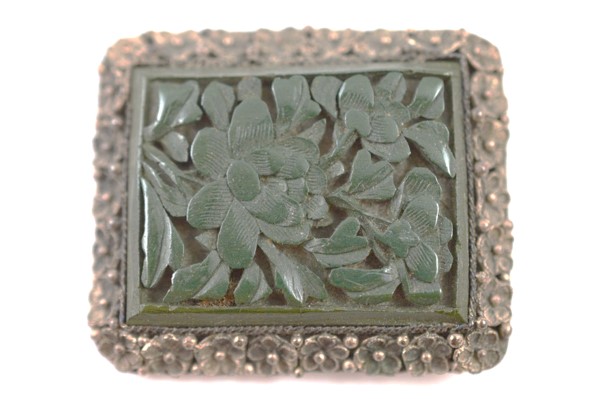 A Chinese and cinnabar lacquer clip, the green floral carved panel within a white metal mount marked