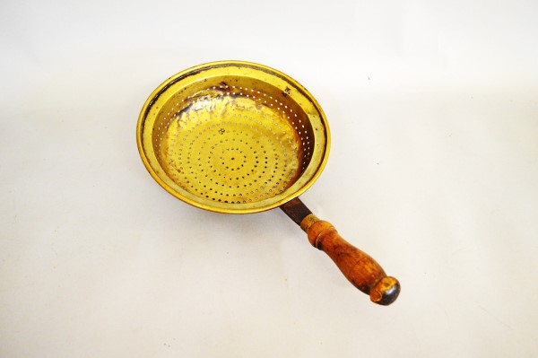 A Victorian brass and turned wooden handled drainer or strainer, the circular brass bowl with