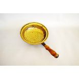 A Victorian brass and turned wooden handled drainer or strainer, the circular brass bowl with