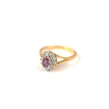 An 18ct gold ruby and diamond cluster ring, the oval mixed cut claw set ruby surrounded by a bezel
