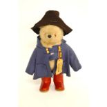 A Gabrielle Designs Paddington Bear, with blue felt jacket, brown hat and red wellington boots,