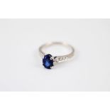 An 18ct white gold sapphire and diamond dress ring, the oval mixed cut claw sapphire in raised