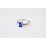 An 18ct gold sapphire and diamond dress ring, the step cut blue sapphire in four claw setting with