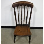 An antique oak spindle back nursing chair shaped back rail, raised on round turned supports,