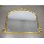 A contemporary arched gilt framed overmantel mirror, of landscape form with a scroll leaf