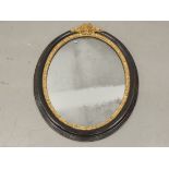 A 20th Century oval mirror with bow motif, 87cm x 66cm