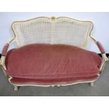 A contemporary continental style settee, cane back, padded arms, the seat upholstered in a pink