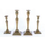 A pair of 18th Century brass candlesticks, on square plinth bases, together with a similar pair,