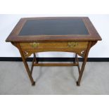 An oak Arts and Crafts writing table, green insert to top, long frieze drawer, raised on flared