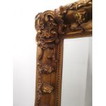 A large 20th Century gilt framed mirror, with brush effect finish and grape vine relief decoration