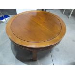 A contemporary oriental style hardwood table, circular grooved top, carving to frieze raised on