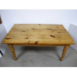 A contemporary waxed pine kitchen table, rectangular top raised on four round turned supports, 152cm
