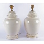 A pair of contemporary pottery lamps, of bulbous form, glazed in white with moulded decoration,