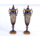 A pair of French porcelain covered jars with cartouches of beauties on a gilt blue ground, each with