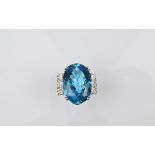 A platinum topaz and diamond dress ring, the large oval mixed cut blue topaz in four claw setting