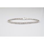 An 18ct gold diamond tennis bracelet, the brilliant cuts in four claw setting on an articulated