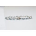 An aquamarine and diamond line bracelet, the oval mixed cut aquamarines in four claw setting