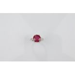 An 18ct gold ruby and diamond dress ring, the circular claw set ruby flanked by pear cut diamonds