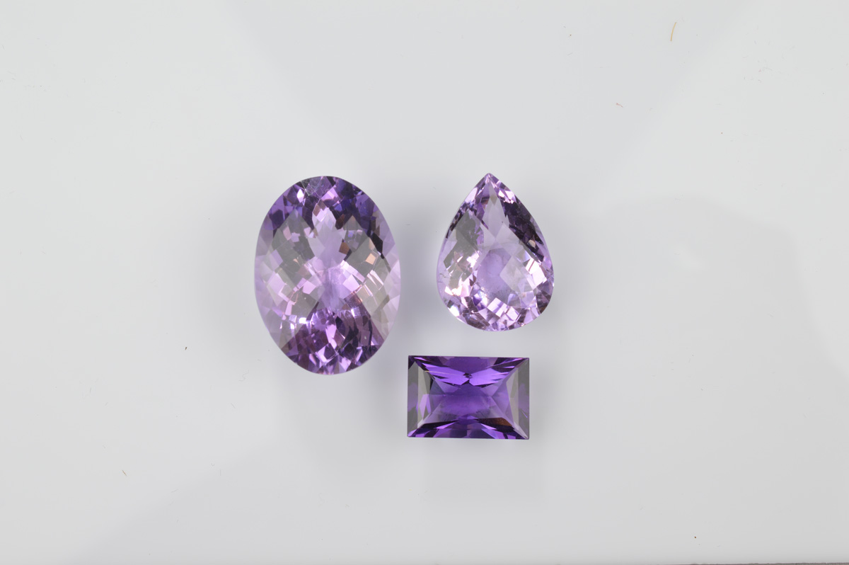 Three certificated loose amethysts, comprising a Uruguayan baguette cut 7.8ct, an oval 27ct and a