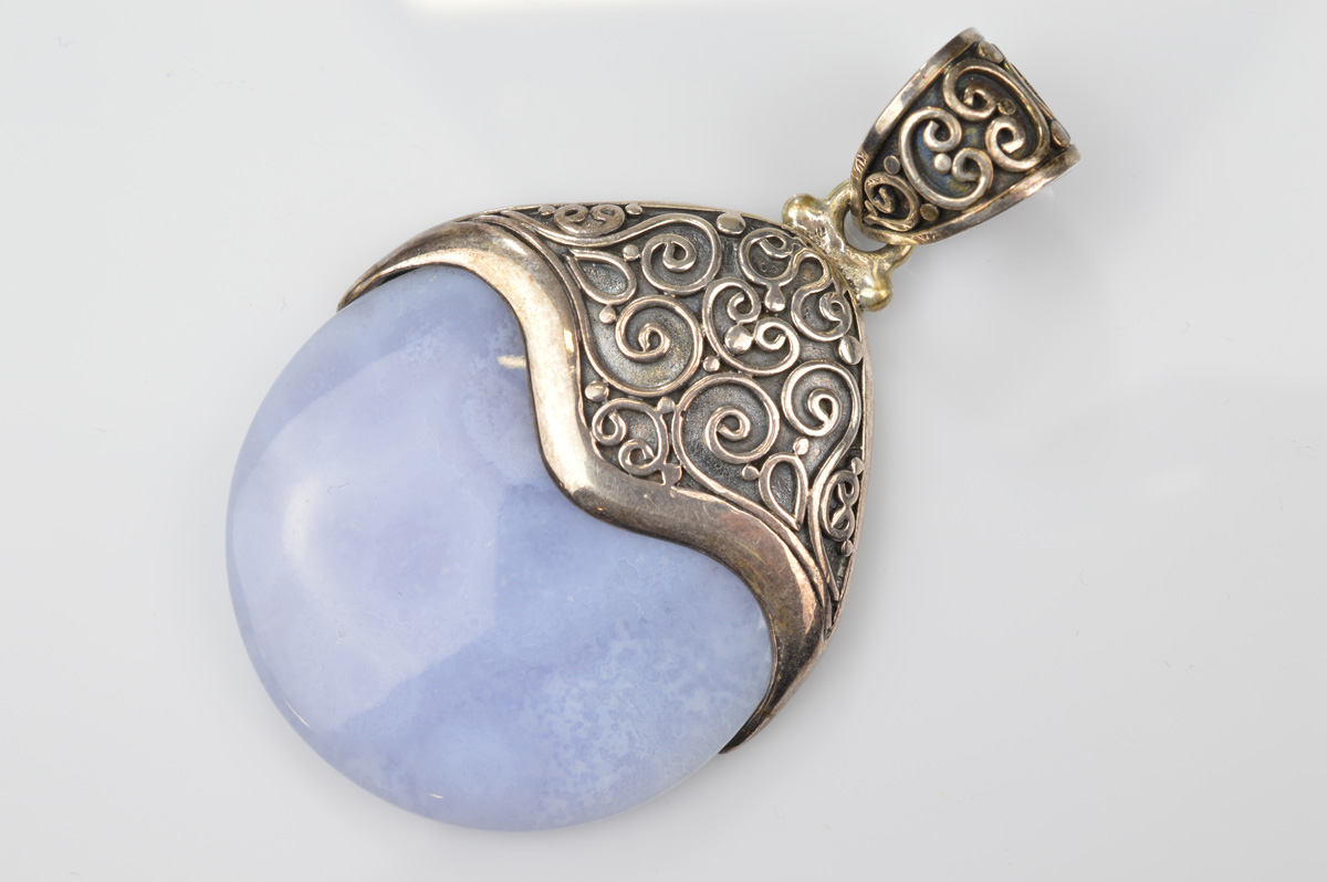 A certificated blue lace agate and silver pendant, the polished disc encased in filigree mount