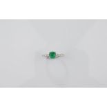 A platinum emerald and diamond dress ring, claw set round cut emeralds with diamond set shoulders