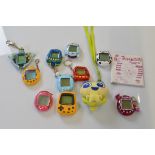 A collection of six Tamagotchis, in pink, yellow, white, and blue together with a Nintendo Pokémon
