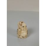 A Japanese bone okimono of a Buddha, with a sack over his shoulder, artist's monogram to base, 6cm