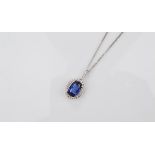 An 18ct gold Ceylon sapphire and diamond pendant, the oval mixed cut claw set sapphire surrounded by