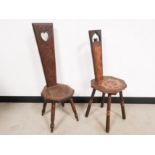 Two carved love chairs or spinning seats, both having decorative carvings to the backrest and